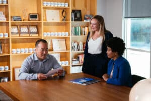 three Atwork employees sitting in a conference room going over paperwork.