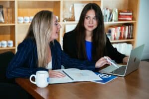 Two female Atowrk employees talking and looking at a computer