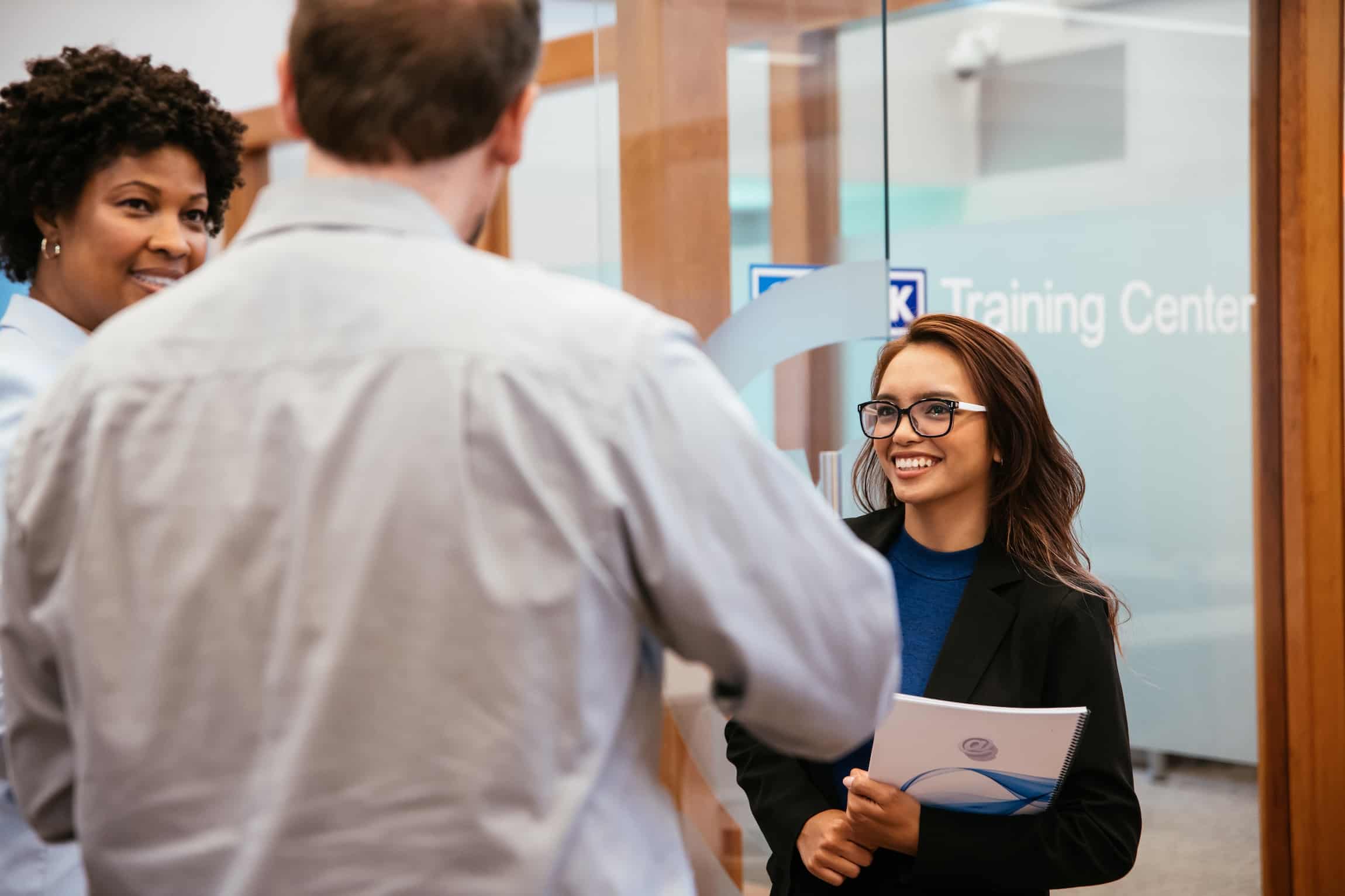 Three atwork coworkers talking with one another in the lobby