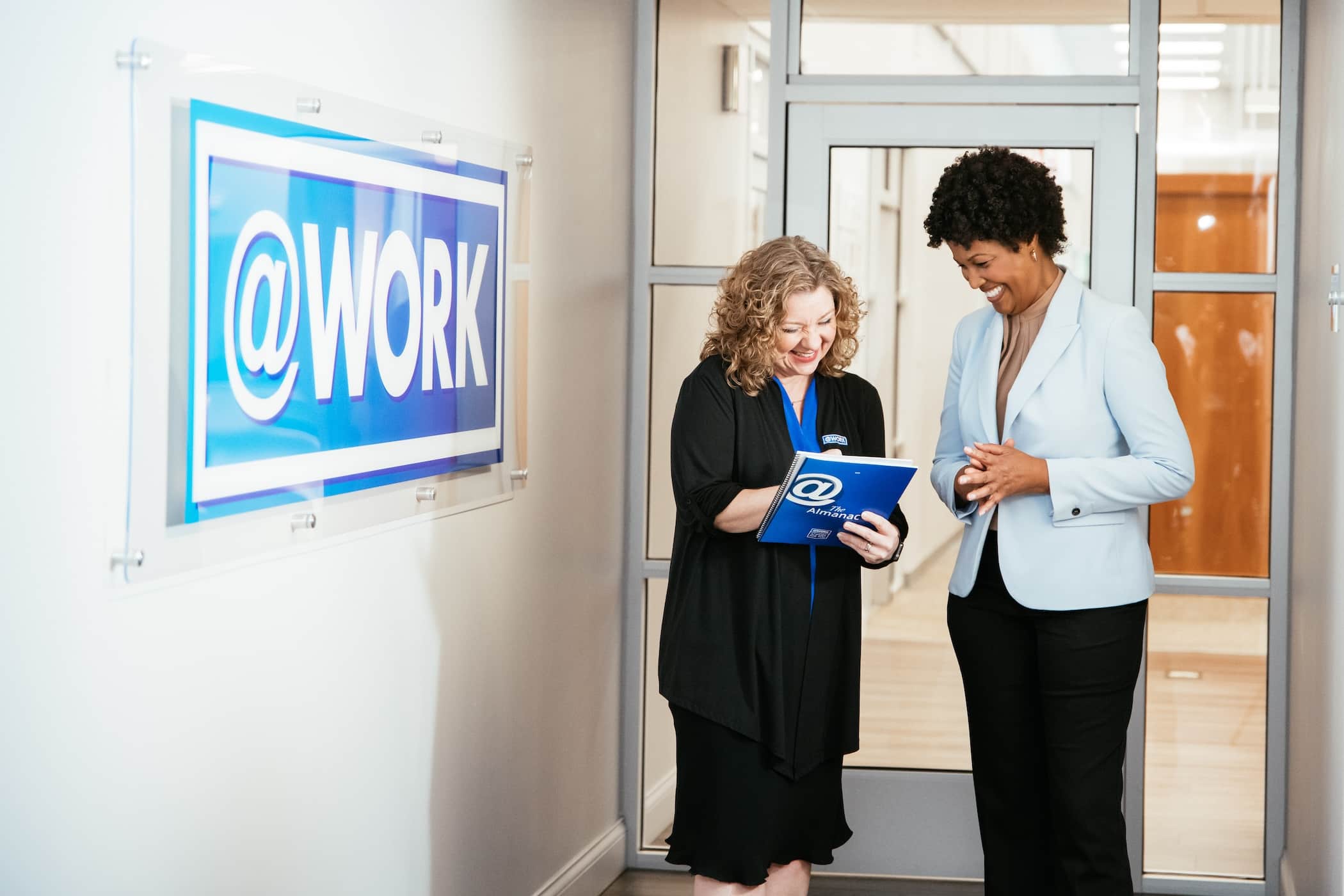 Two Atwork employees reviewing paperwork in an office hallway