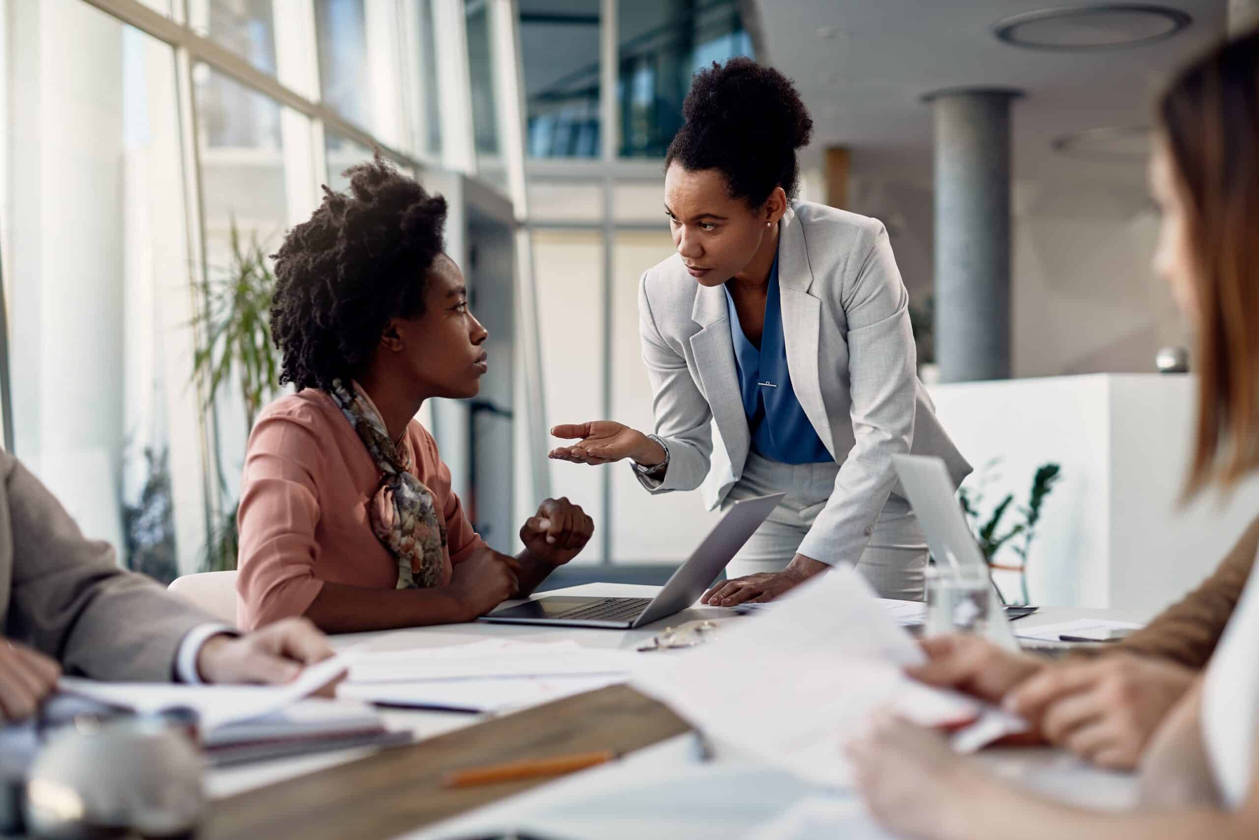 Female CEO discusses with business apprentice on meeting at corporate office.